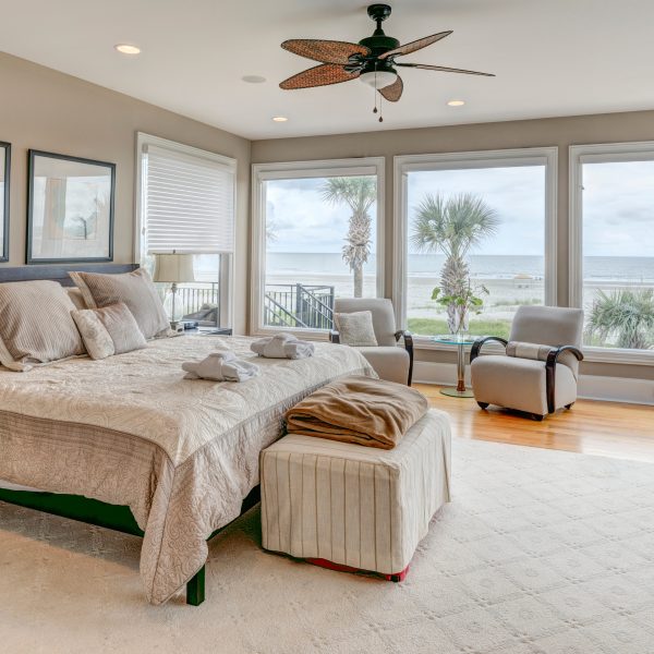 Luxury beach view bedroom looking out onto palm trees and the ocean.